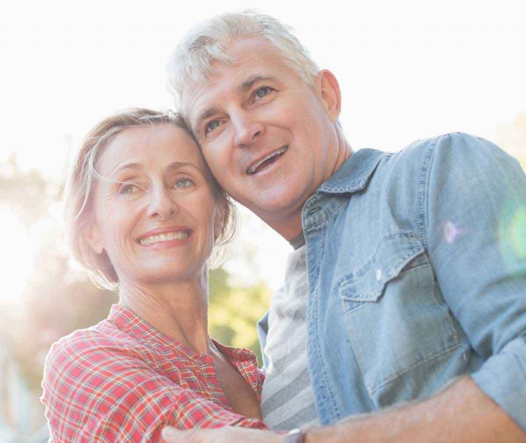 Happy middle age couple hugging and enjoying life with hearing aids.